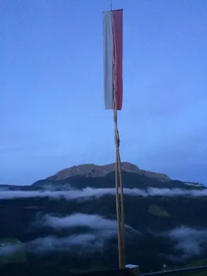 a flag on top of a mountain with clouds at Oeberst-hof in Sarntal