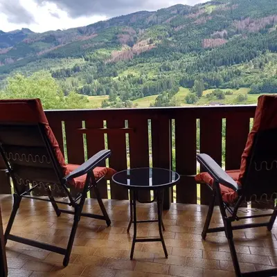 a balcony with two chairs and a table and a mountain at Casa Luisa in Tesero