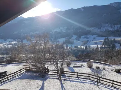 a snow covered field with a fence and mountains at Casa Luisa in Tesero