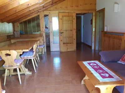 a living room with a wooden table and chairs at Casa Luisa in Tesero