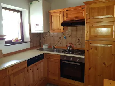 a kitchen with wooden cabinets and a stove top oven at Casa Luisa in Tesero