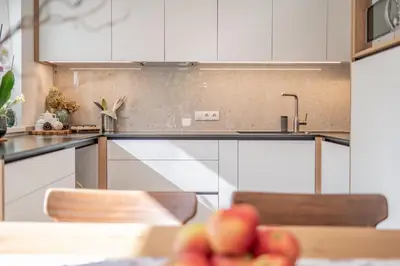 a kitchen with white cabinets and a table with apples at BioTop Appartement Kronplatz in Perca