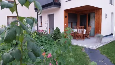 a patio with a table and chairs in a garden at BioTop Appartement Kronplatz in Perca