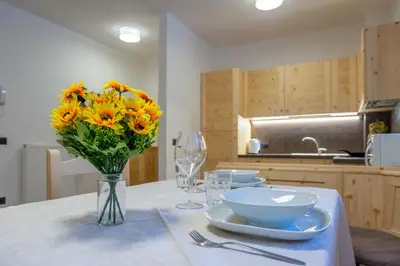 a table with a vase of sunflowers in a kitchen at Appartamento Alessia in Rocca Pietore