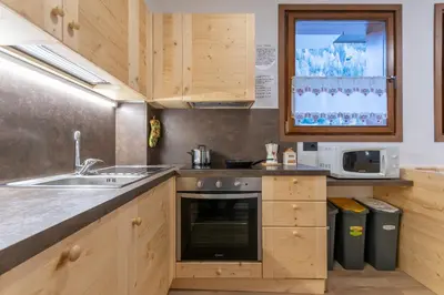a kitchen with wooden cabinets and a sink and a microwave at Appartamento Alessia in Rocca Pietore