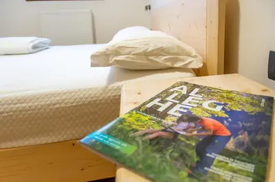 a magazine sitting on a table next to a bed at Appartamento Alessia in Rocca Pietore