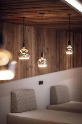 two chairs in a room with lights hanging from the ceiling at ROUDA luxury retreat am Kronplatz in Valdaora