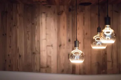 a couple of lights hanging from a wooden wall at ROUDA luxury retreat am Kronplatz in Valdaora