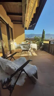 a bed on a patio with a table and chairs at LAnJA ihr besonderes Urlaubszuhause in Lagundo