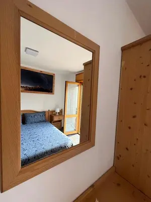 a mirror in a bedroom with a bed in it at Dolomitihouse LARES in Fiera di Primiero