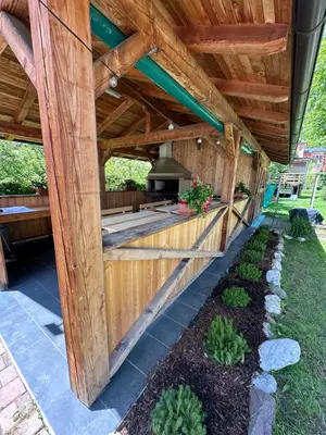 an outdoor kitchen with a wooden pergola at Dolomitihouse LARES in Fiera di Primiero