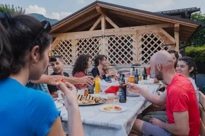 a group of people sitting at a table eating pizza at Dolomitihouse LARES in Fiera di Primiero
