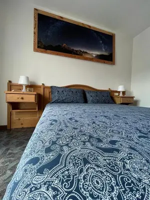 a bedroom with a bed with a blue and white bedspread at Dolomitihouse LARES in Fiera di Primiero