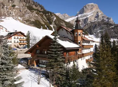 a building in the snow in front of a mountain at Piz Alpin B&B in Colfosco