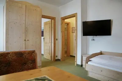 a bedroom with a bed and a tv and a couch at Piz Alpin B&B in Colfosco