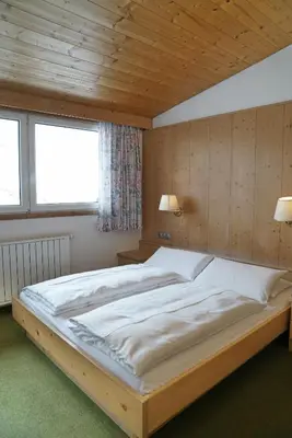 a large bed in a bedroom with a wooden ceiling at Piz Alpin B&B in Colfosco