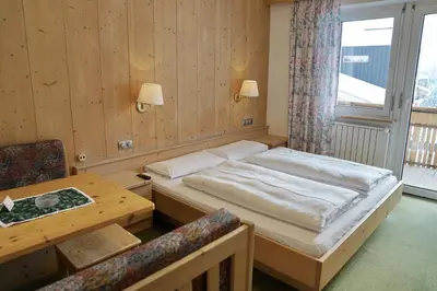 a bedroom with a bed and a table and a window at Piz Alpin B&B in Colfosco