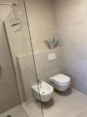 a bathroom with a toilet and a glass shower at Casa Grutzen Design Apartment with Pool in Bolzano in Bolzano