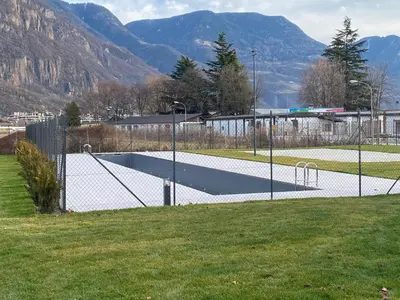 a tennis court in a field with mountains in the background at Casa Grutzen Design Apartment with Pool in Bolzano in Bolzano