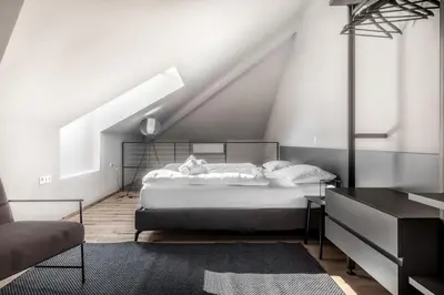 a white bedroom with a bed and a chair at Stay COOPER l CITY LOFT in Bolzano