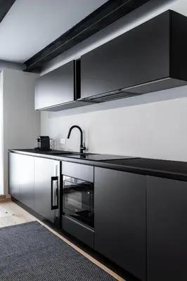 a kitchen with black cabinets and a sink at Stay COOPER l CITY LOFT in Bolzano