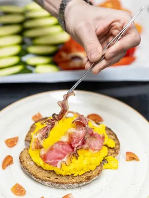 a person is eating a breakfast sandwich on a plate at Stay COOPER l CITY LOFT in Bolzano