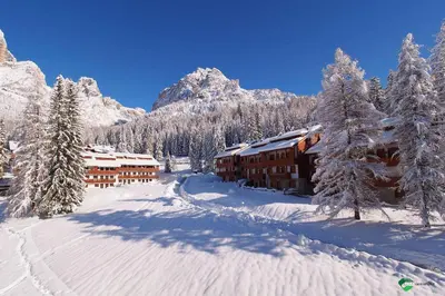 a ski lodge in the mountains with snow covered trees at Petit Arnica in Selva di Cadore