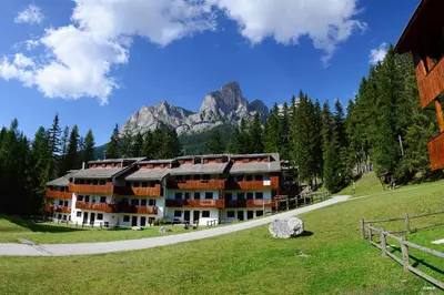 a large building with a mountain in the background at Petit Arnica in Selva di Cadore