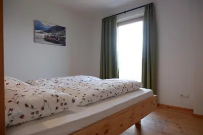 a bed with a comforter and a window at Wolfhof_Ritten in Auna di Sopra