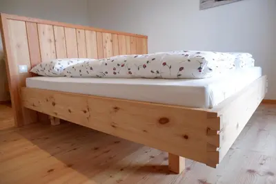 a wooden bed with two pillows on top of it at Wolfhof_Ritten in Auna di Sopra