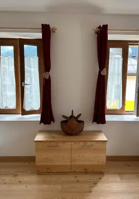 a room with two windows and a wooden chest at Casa Felice in Caviola