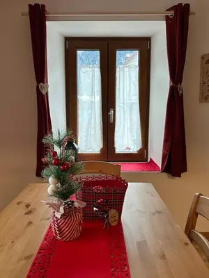 a room with a table with a christmas tree on a red rug at Casa Felice in Caviola