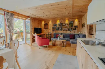 a kitchen and living room with wooden walls at Luxury Chalet Liosa - Ski in Ski out - Amazing view in Corvara in Badia