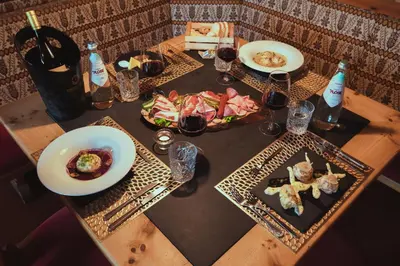 a wooden table with plates of food and glasses of wine at PLOSE Parkhotel & Residence in Bressanone