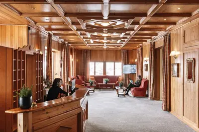 a woman sitting at a reception desk in a lobby at PLOSE Parkhotel & Residence in Bressanone