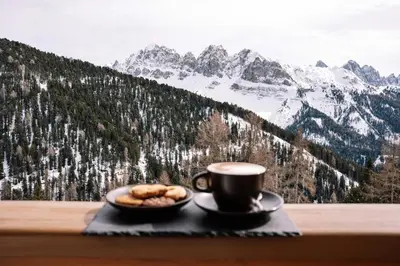 a cup of coffee and a plate of donuts on a table at PLOSE Parkhotel & Residence in Bressanone
