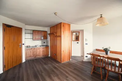 a kitchen with wooden cabinets and a wooden table at PLOSE Parkhotel & Residence in Bressanone