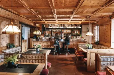 a restaurant with wooden ceilings and tables and chairs at PLOSE Parkhotel & Residence in Bressanone