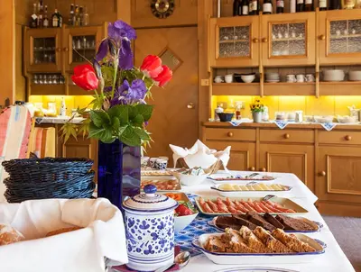a table with plates of food and flowers on it at Pension an der Mayenburg in Vollan