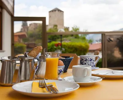 a table with plates of food and a glass of orange juice at Pension an der Mayenburg in Vollan