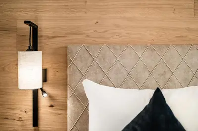 a bedroom with a bed with a lamp and a headboard at Apartments Belaval in Santa Cristina in Val Gardena