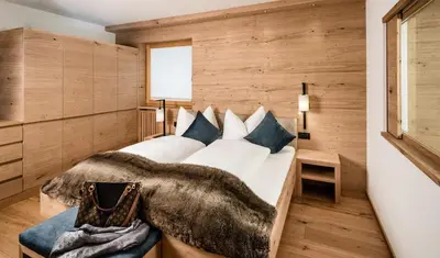 a bedroom with a large white bed with blue pillows at Apartments Belaval in Santa Cristina in Val Gardena