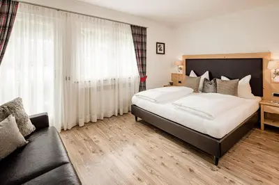 a bedroom with a large bed and a couch at Apartment Bellaria in Santa Cristina in Val Gardena