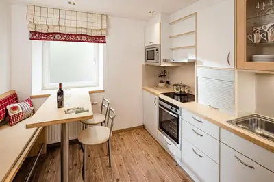 a kitchen with white cabinets and a table and chairs at Apartment Bellaria in Santa Cristina in Val Gardena