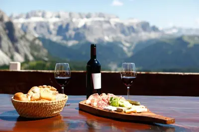 a table with two glasses of wine and a plate of food at Apartment Bellaria in Santa Cristina in Val Gardena