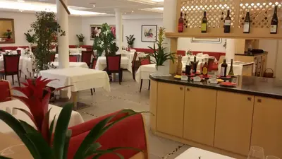 a restaurant with tables and chairs and wine bottles at Hotel Maximilian in Merano
