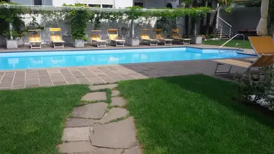 a swimming pool with chairs and a bench in a yard at Hotel Maximilian in Merano