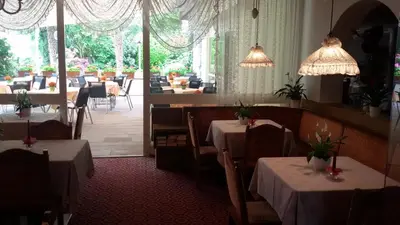 a dining room with tables and chairs and a restaurant at Hotel Maximilian in Merano