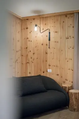 a bedroom with a green couch and wooden walls at Rooms Kronblick in San Lorenzo di Sebato