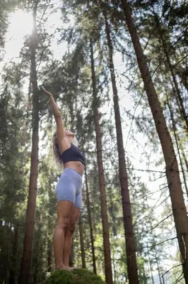 a woman standing on a rock in the forest at Rooms Kronblick in San Lorenzo di Sebato